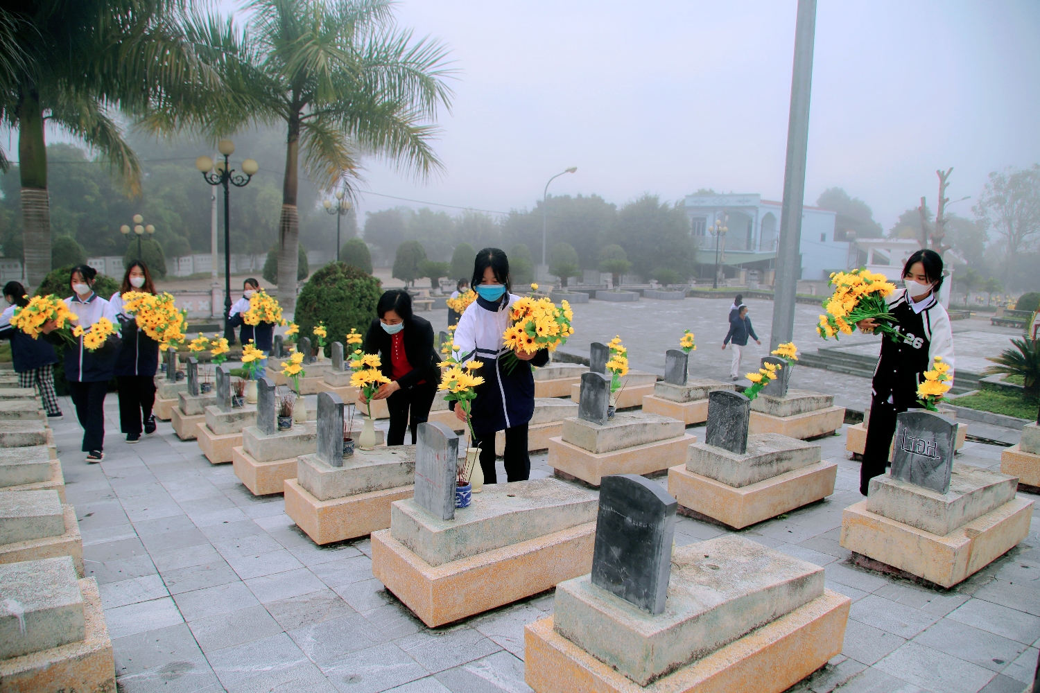Cô Lê Kiều Oanh cùng HS trường THPT Thanh Nưa cùng chăm sóc, thay hoa tại các phần mộ liệt sĩ